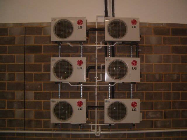 Multi-unit condenser bank mounted to brick wall — air-conditioning install by Cool Solutions.